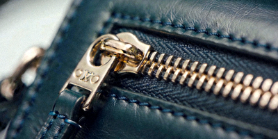 放大镜检查奢侈品包包细节如缝线和五金的高清特写图片