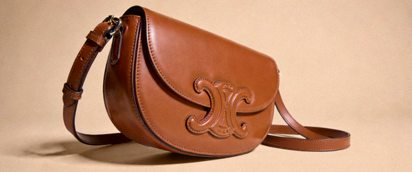 焦糖色马鞍斜挎包高清侧面实拍，突出独特的弧形包身和浮雕logo