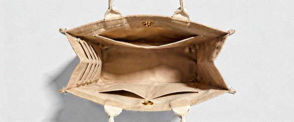 设计师品牌经典米色帆布托特包高清实拍，展示正面大容量主隔层和侧边口袋细节