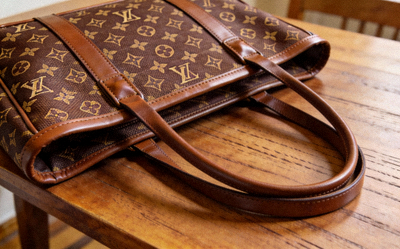 Brown monogram canvas replica tote bag with leather trim and dual handles on a wooden table