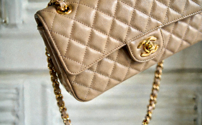 Chanel Classic Flap Medium bag in beige caviar leather with gold hardware, shown from the side with chain strap