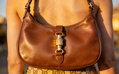 Gucci Jackie 1961 small hobo bag in smooth brown leather with iconic piston closure, carried on the shoulder