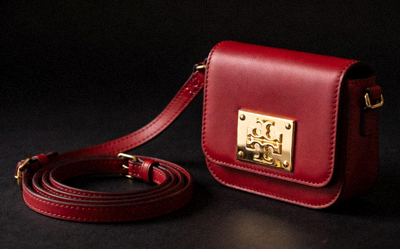 Mini replica crossbody bag in red with gold logo plaque and adjustable strap against a dark background