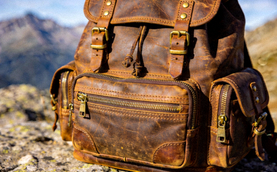 Rugged leather backpack with multiple compartments and brass zippers for outdoor use