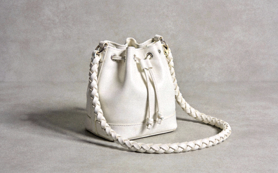 White replica bucket bag with drawstring closure and braided handle on a light gray surface